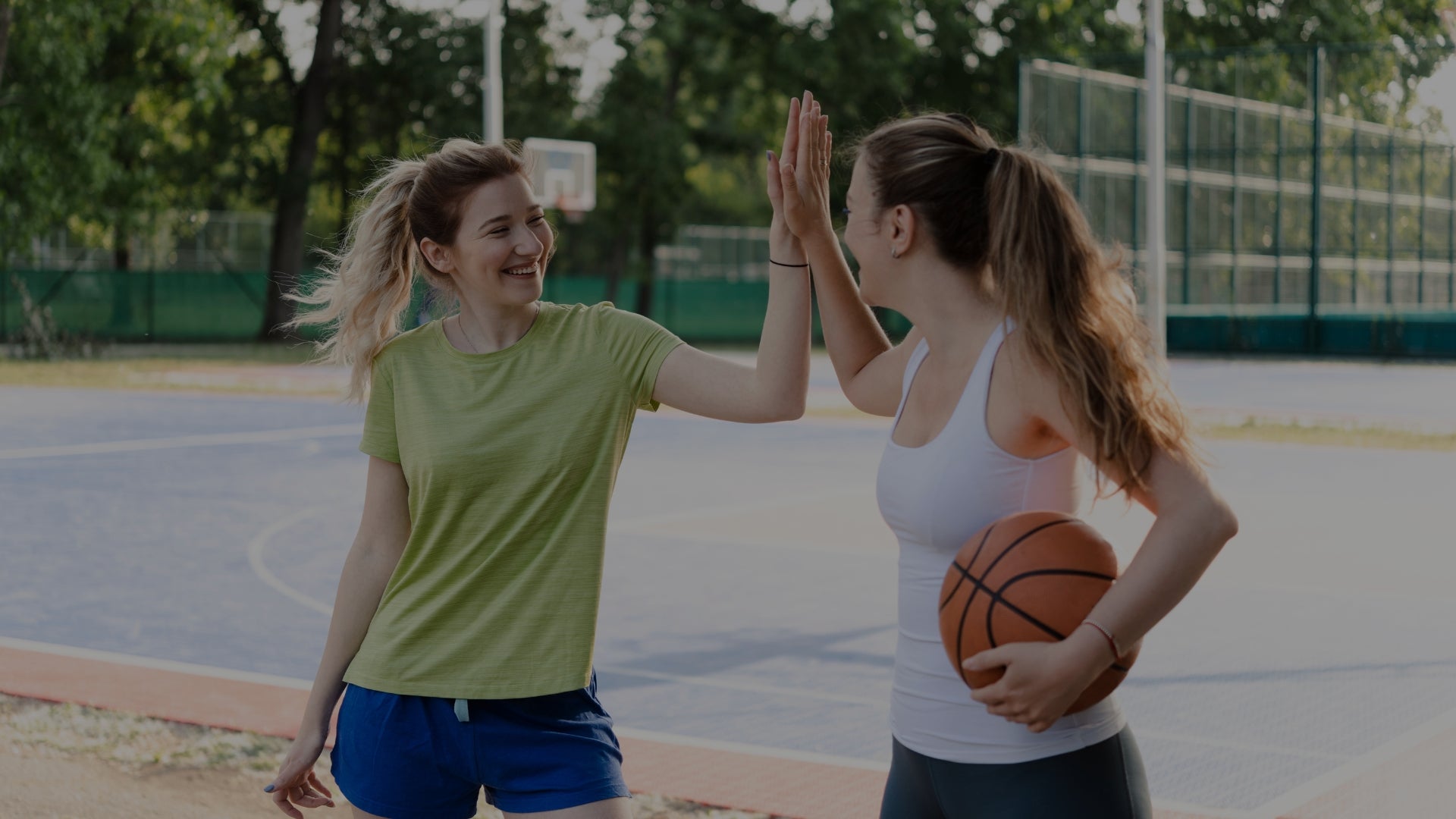 Two women on a basketball court giving each other a high-five.